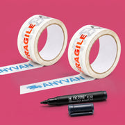 Two rolls of white AnyVan fragile tape and a black Ikon K30 permanent marker, on a pink background