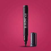 A black Ikon K30 Permanent Marker with its cap removed and standing beside it, set against a solid magenta-pink background.