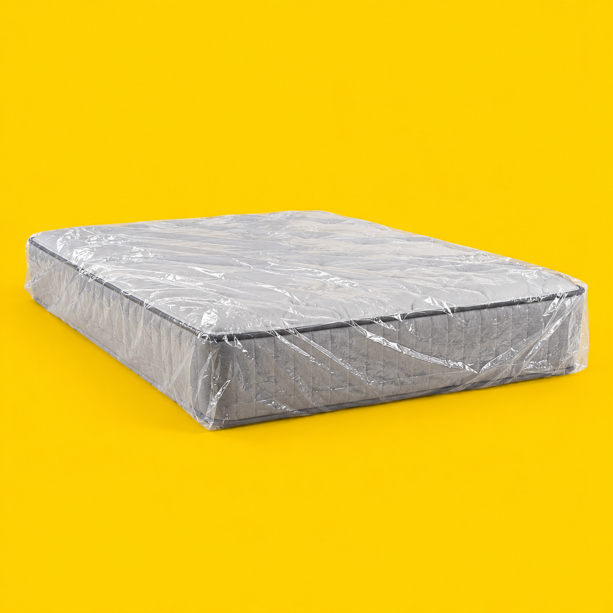 A mattress wrapped in a clear plastic protective cover, on a yellow background
