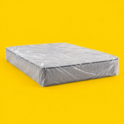A mattress wrapped in a clear plastic protective cover, on a yellow background