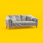 A grey three-seater sofa covered in a clear plastic protective cover, seen at an angle on a yellow background